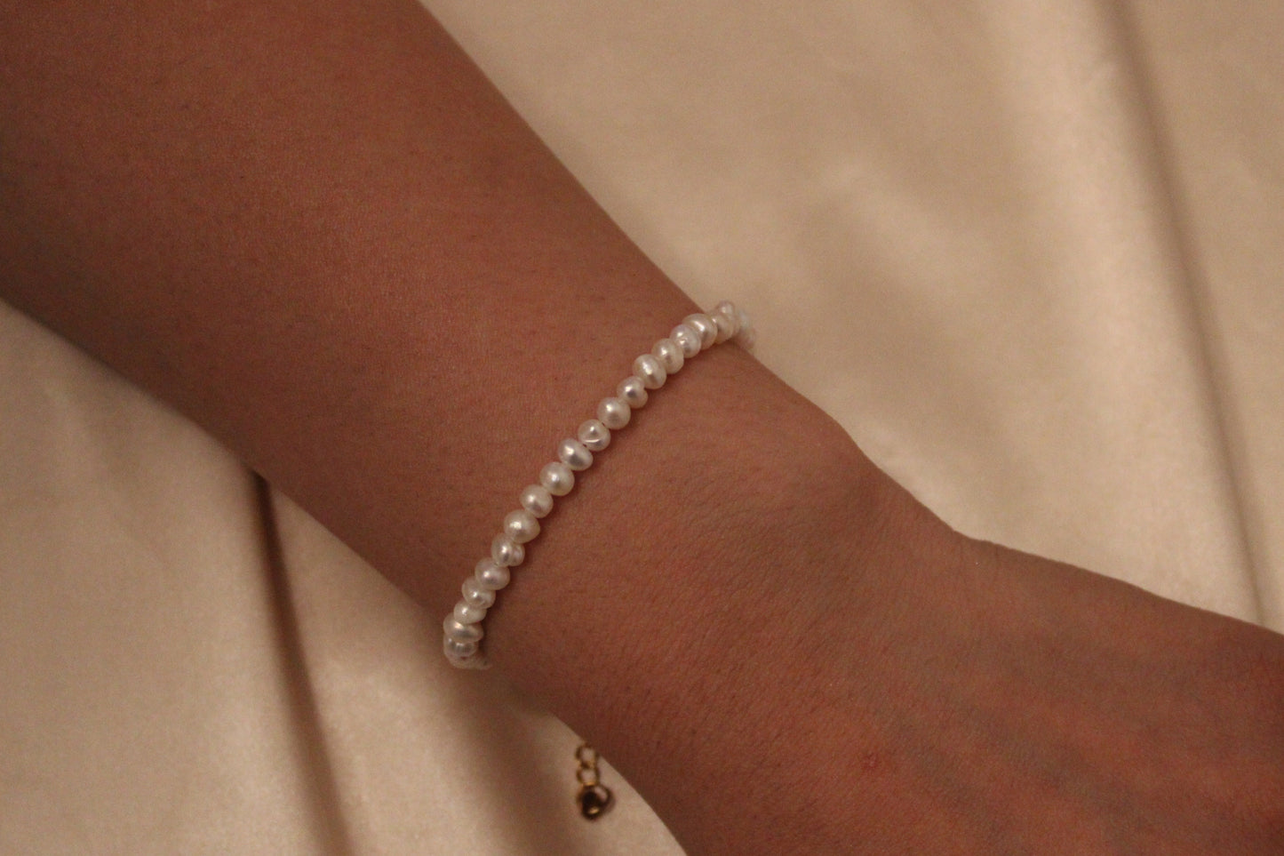 Close-up van sluiting en 4 mm zoetwaterparel op een goudkleurige stainless steel armband om de pols