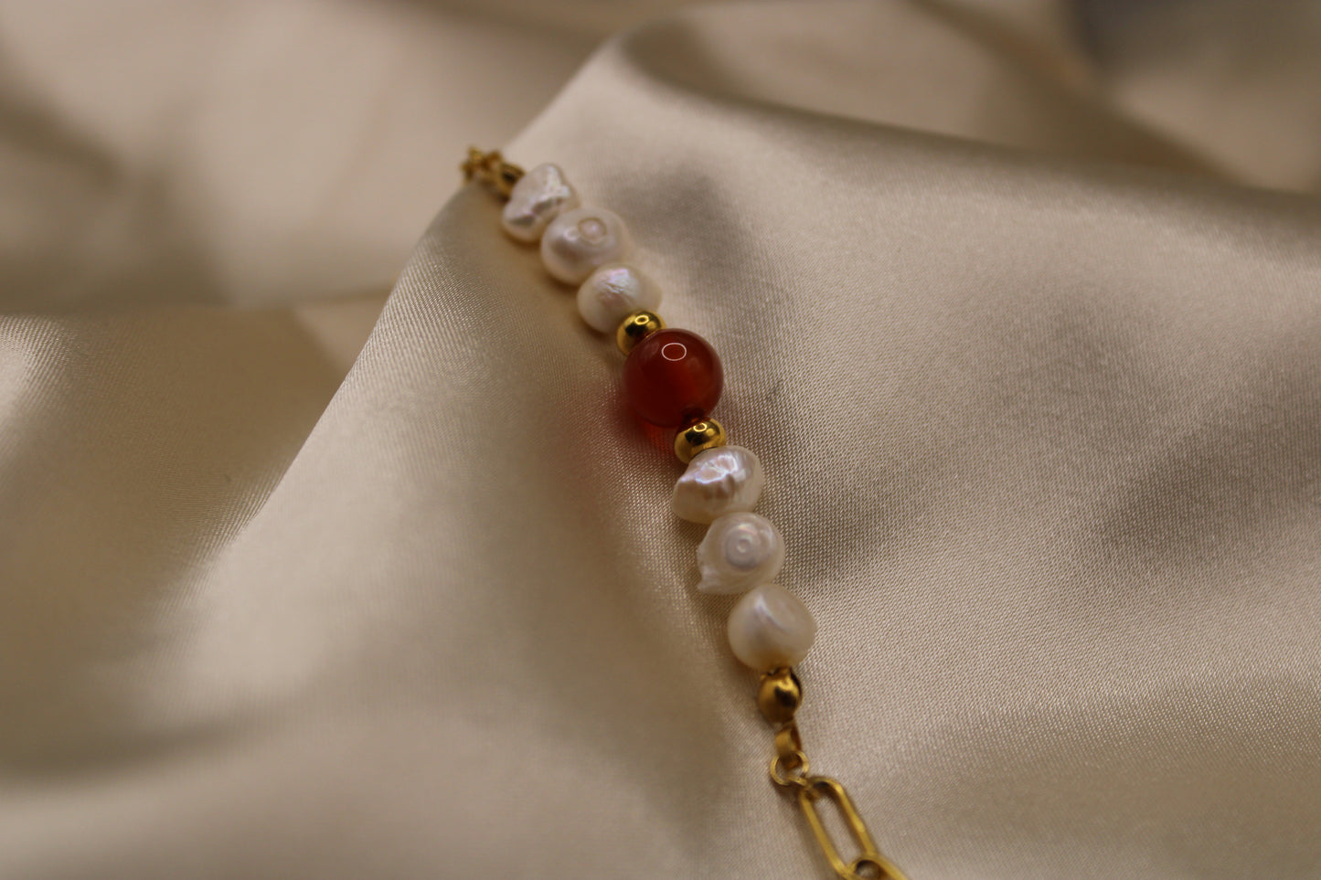 Elegant ontwerp van carneool edelsteen en parels, gecombineerd met een goudkleurige stainless steel armband.