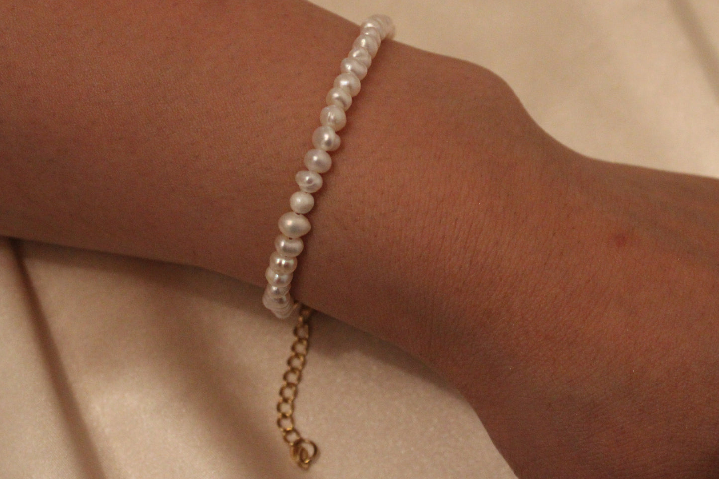 Pols met verfijnde armband van goudkleurig stainless steel en 4 mm zoetwaterparel