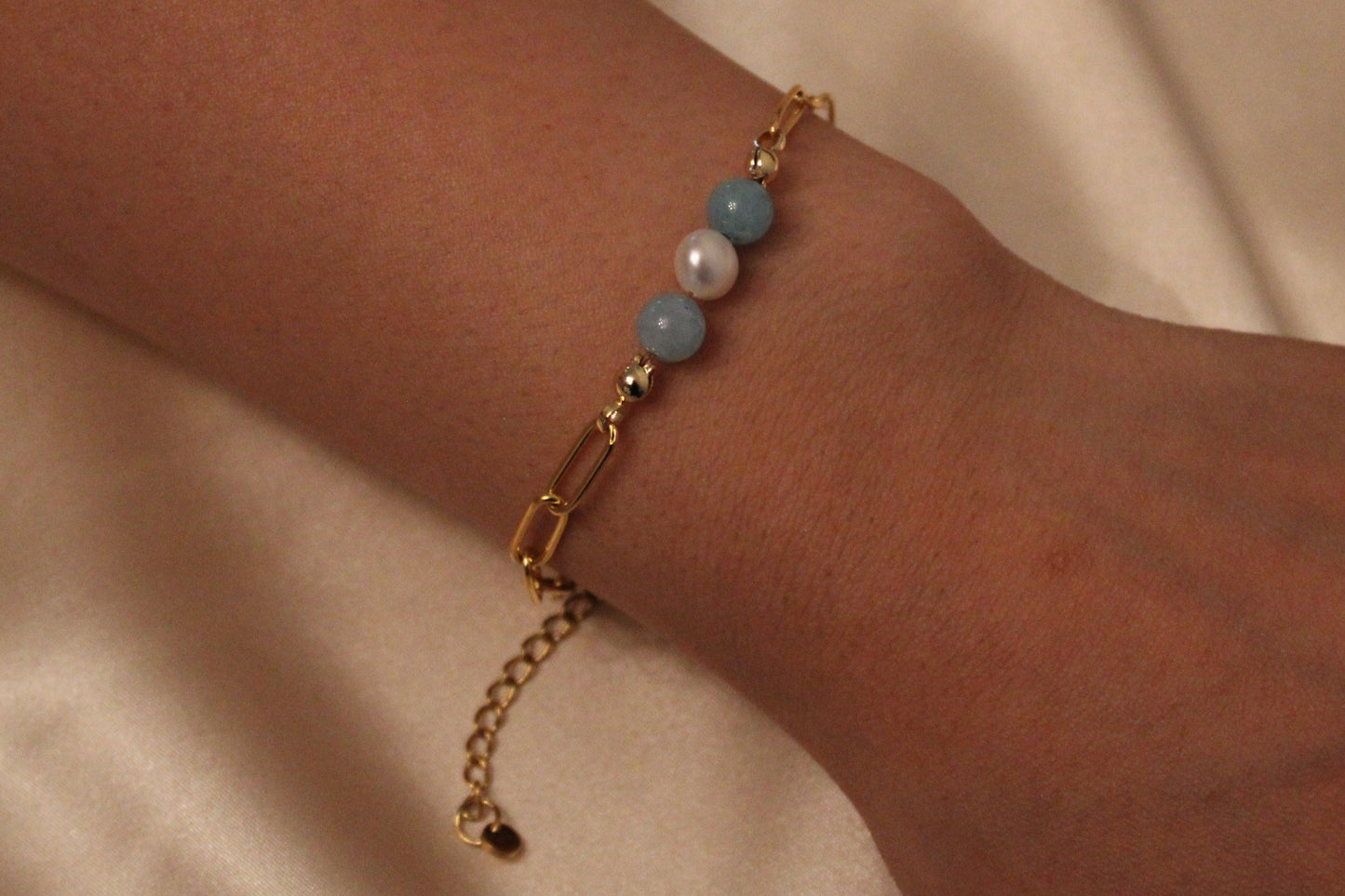 Damespols met stijlvolle armband van aquamarijn en witte parels in goudkleurige afwerking