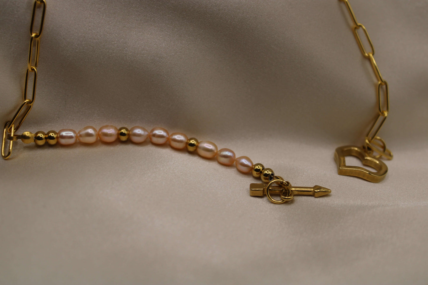 Goudkleurige ketting van stainless steel met roze zoetwaterparels en hart als sluiting.