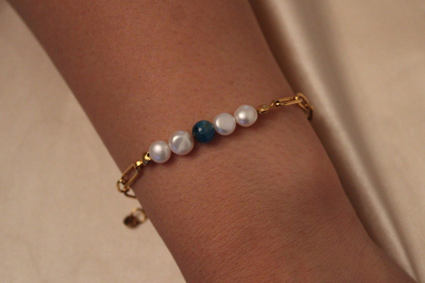 Pols van vrouw met elegante armband van stainless steel, apatiet en zoetwaterparels