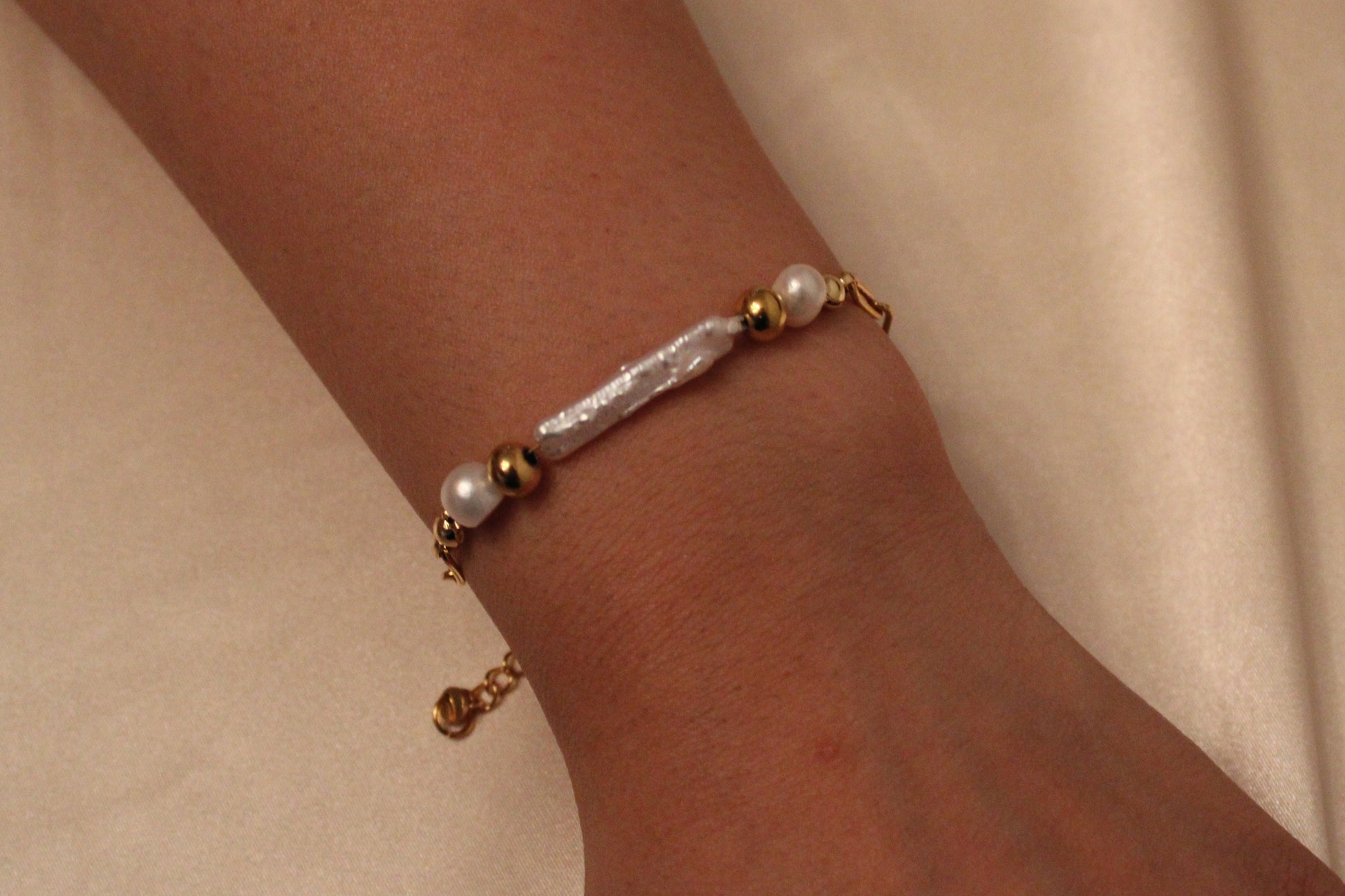Minimalistische handgemaakte armband met grote parel en goudkleurige kralen – gedragen aan de pols