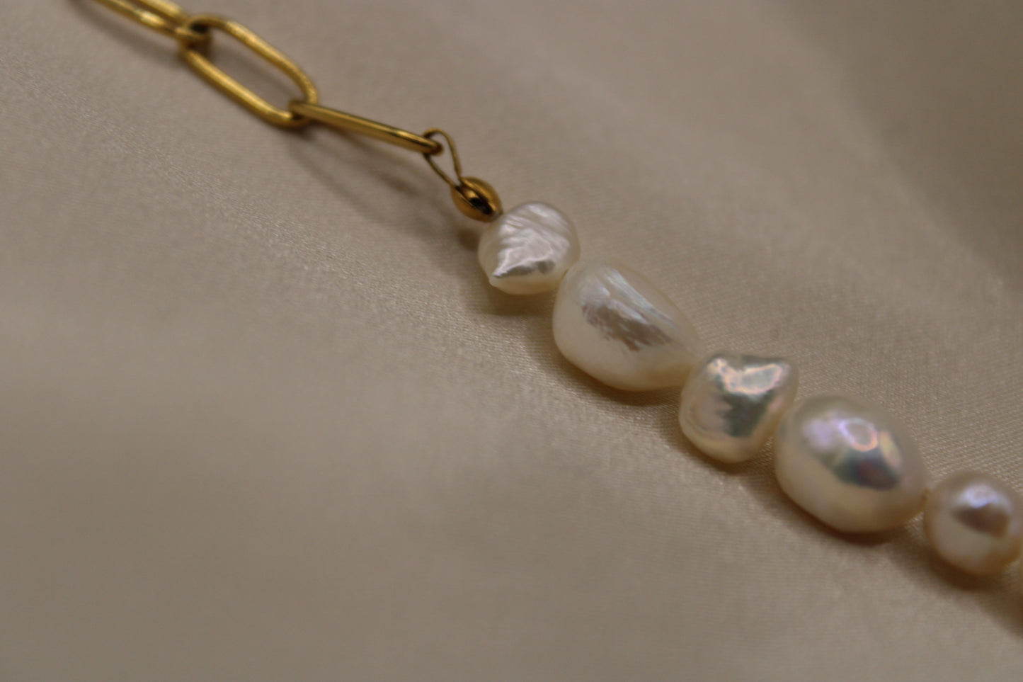 Elegante zoetwaterparel armband met duurzame roestvrijstalen accenten in goudkleur.