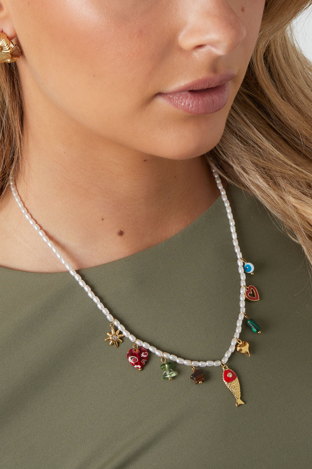 Middellange ketting met vis en hart hanger – kleurrijke emaille ketting, gedragen door model voor een zomerse look