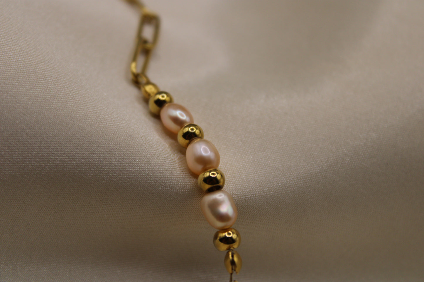 Goudkleurige stainless steel armband met roze zoetwaterparels en kralen van rvs - een chic en verfijnd sieraad.
