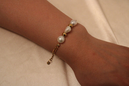 Minimalistische handgemaakte armband met 3 parels en 2 gouden kralen, gedragen aan een pols