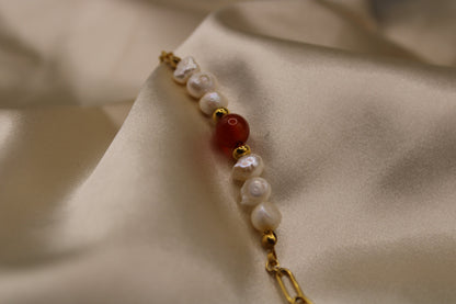 Elegant ontwerp van carneool edelsteen en parels, gecombineerd met een goudkleurige stainless steel armband.
