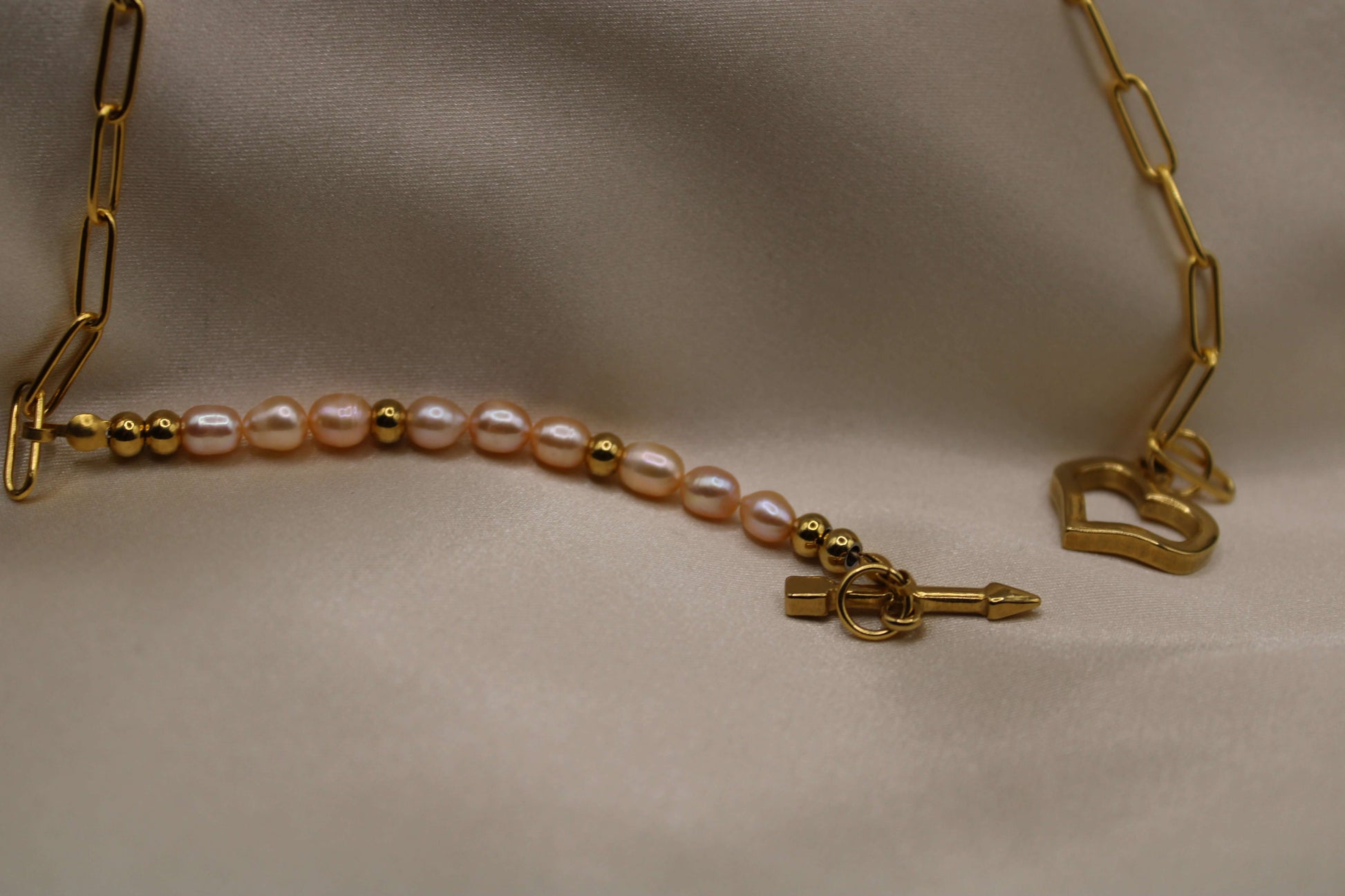 Goudkleurige ketting van stainless steel met roze zoetwaterparels en hart als sluiting.