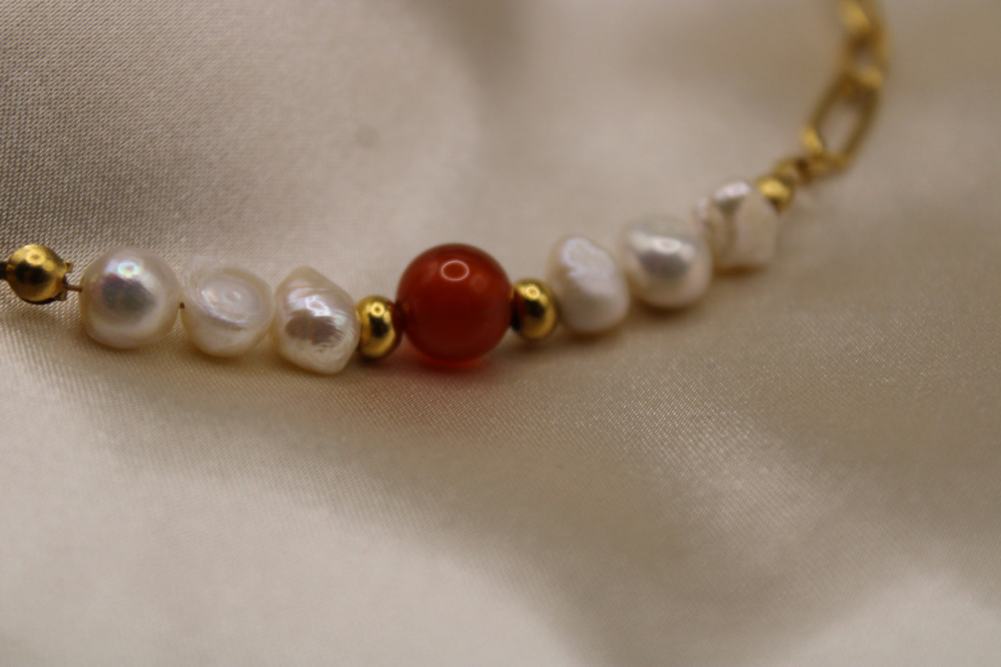 Armband van carneool edelsteen en parels, met goudkleurig stainless steel als materiaal.
