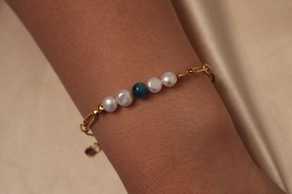Pols van vrouw met elegante armband van stainless steel, apatiet en zoetwaterparels
