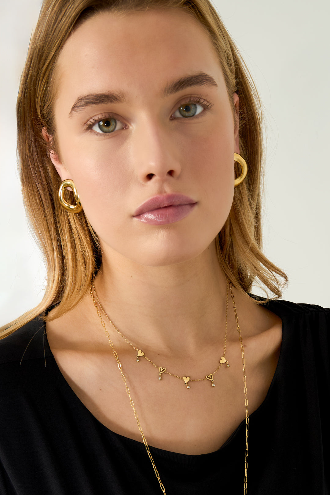 Hart schakelkettig – korte goudkleurig ketting met hartdetails en strass, gedragen rond de hals
