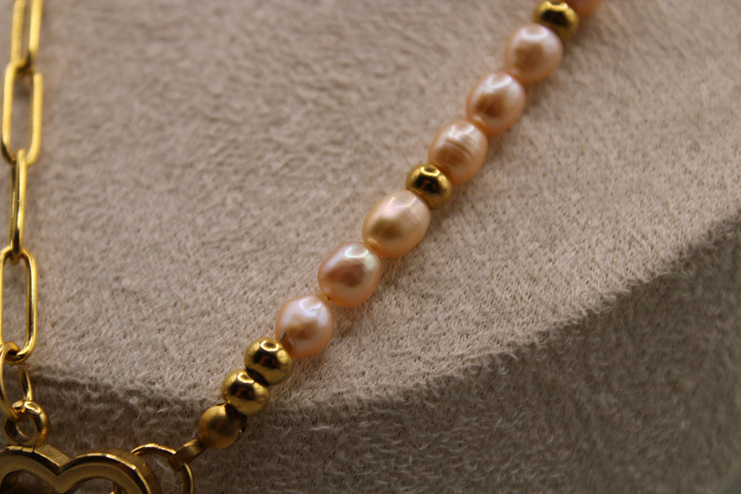 Ketting met roze zoetwaterparels, goudkleurige accenten en hartvormige sluiting.