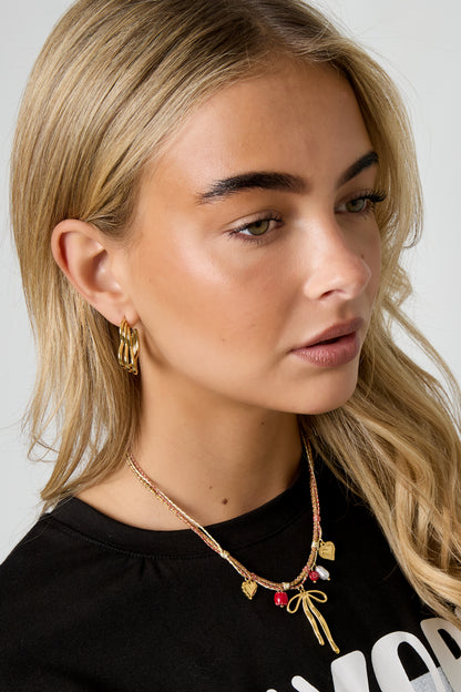 Ketting met strik en hart hanger – goudkleurig ketting met strik en hart hanger, gedragen rond de hals