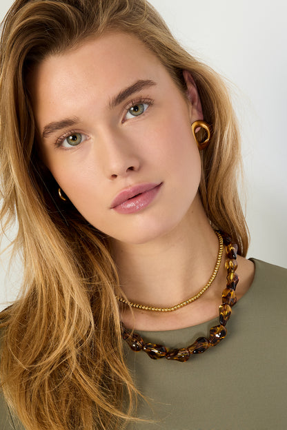 Korte retro kralenketting – bruine kralenketting gedragen rond de hals voor een stoere, vintage look
