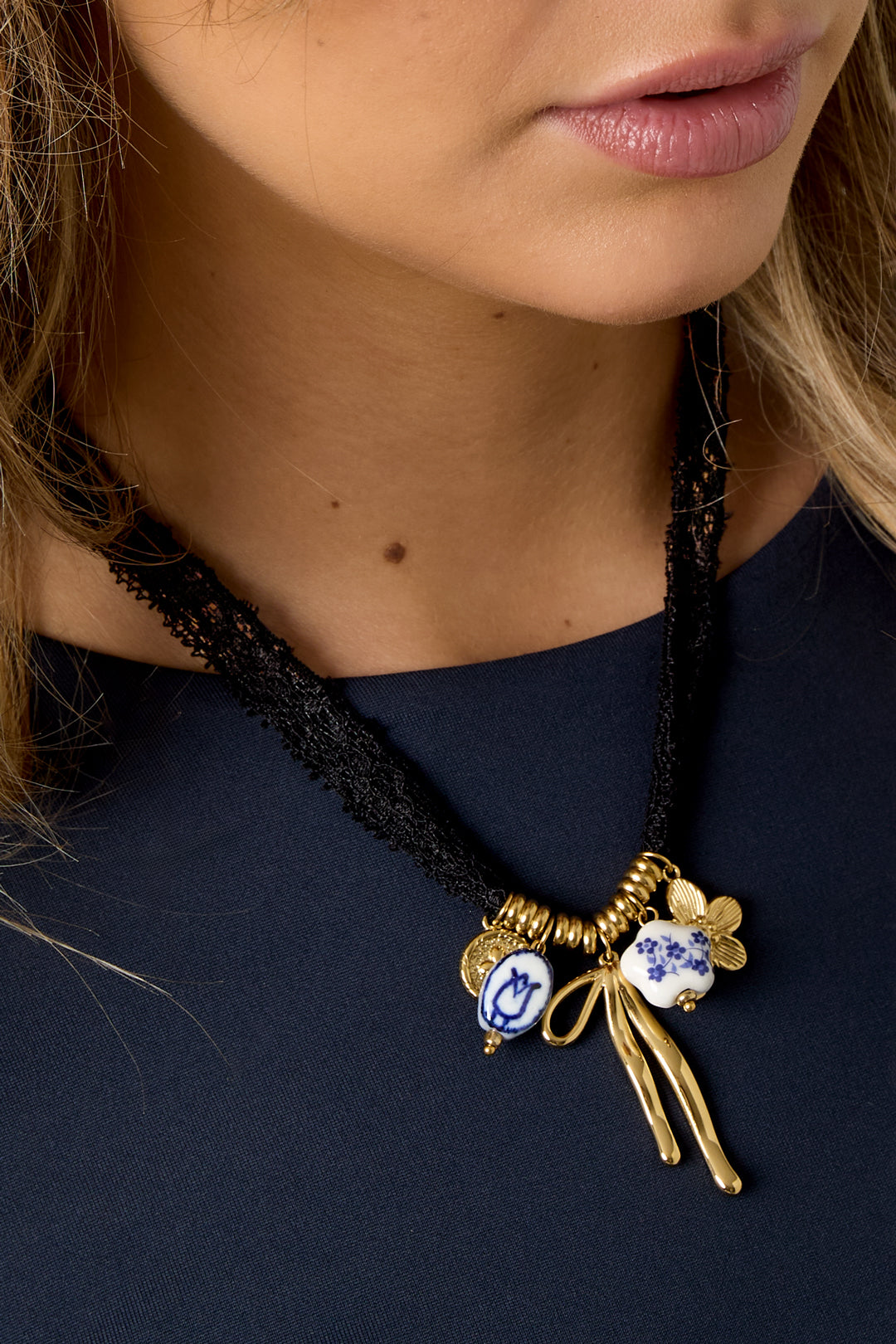 Close-up van lange ketting met bloemen en strik – romantische lintketting met goudkleurige details rond de hals