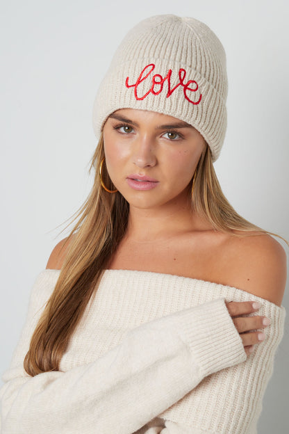 Model draagt een khaki Love It dames wintermuts met ‘Love’ borduursel