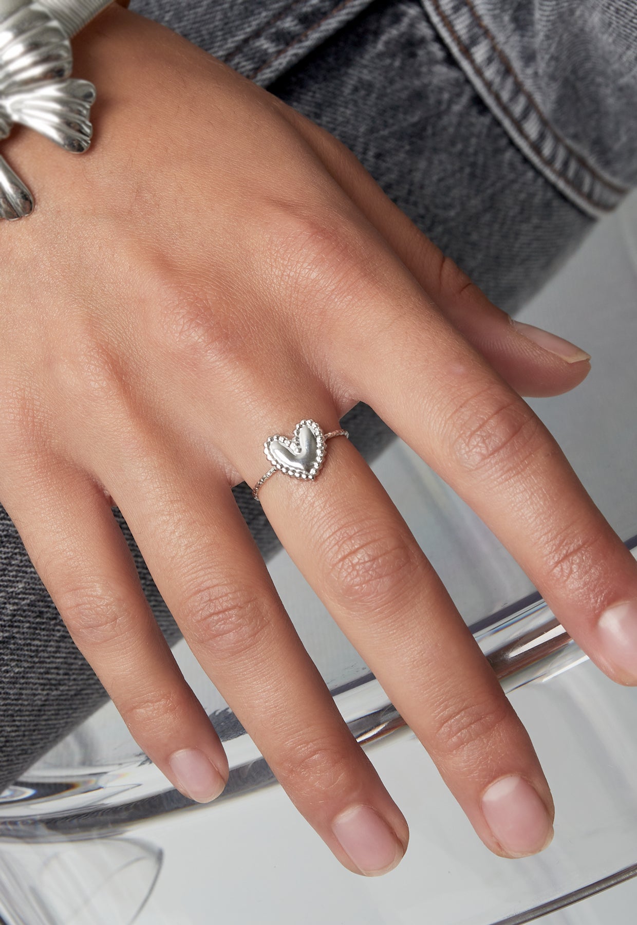 Lover girl ring met zilverkleurig hartdetail aan dameshand met meerdere ringen