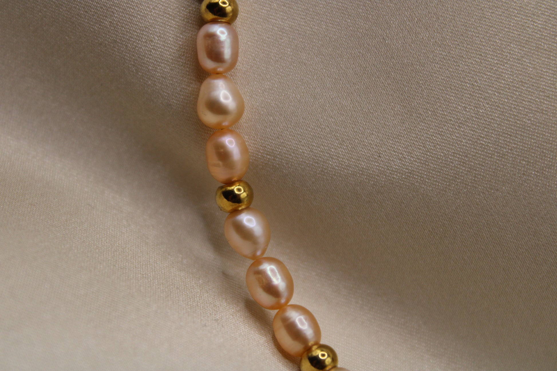 Roze parelketting van stainless steel met gouden kralen en hartsluiting.