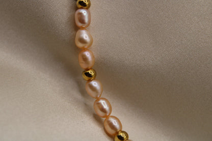 Roze parelketting van stainless steel met gouden kralen en hartsluiting.