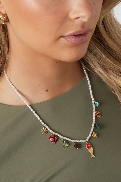 Middellange ketting met vis en hart hanger – kleurrijke emaille ketting, gedragen door model voor een zomerse look