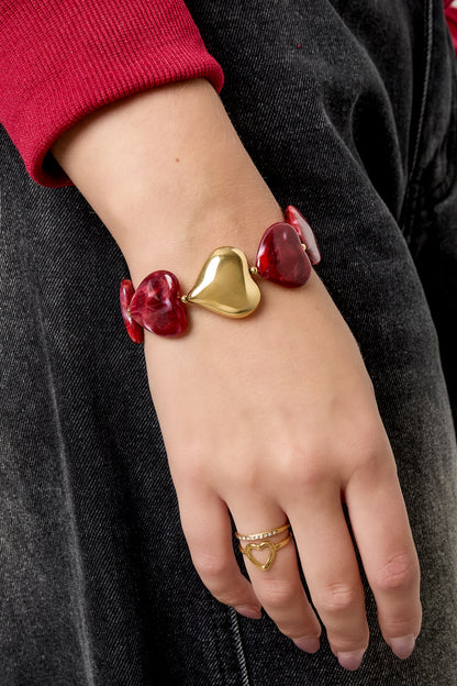 Model draagt retro armband met crimson hartkralen en goudkleurige details aan de pols