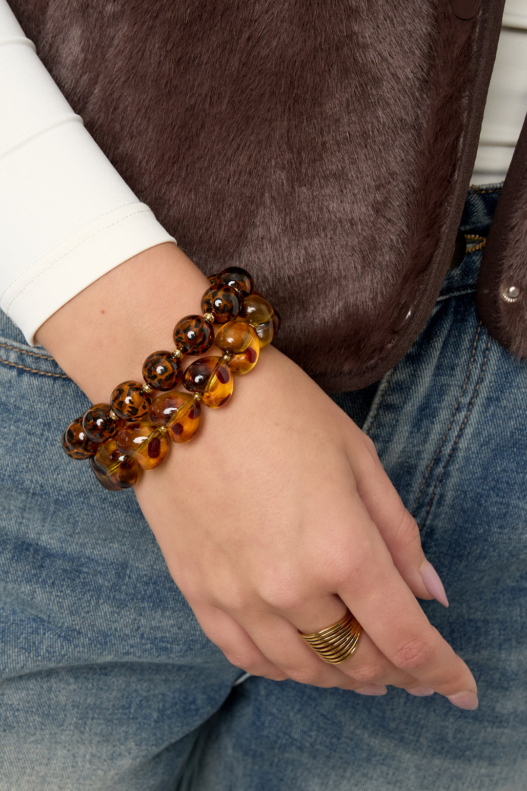 Model draagt retro armband met panterprint kralen in een speelse, gelaagde armband look